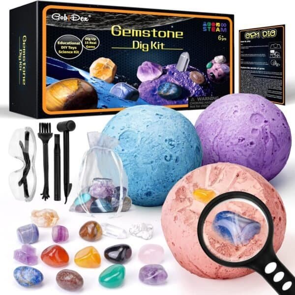Gemstone dig kit with three colored excavation rocks, various digging tools, safety goggles, assorted gemstones, and a magnifying glass, with packaging in the background.