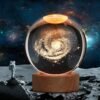 An astronaut stands on a rocky surface, gazing at a Large 3D Galaxy Crystal Ball Night Light with 16 color-changing options and remote control, set against a star-filled space background—perfect for bedroom decor or as a unique birthday gift.