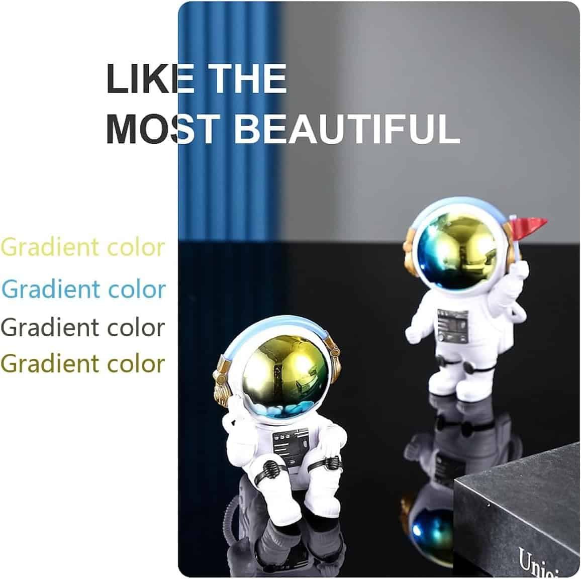 Two small astronaut figurines with gold visors stand on a reflective black surface; text beside them reads "LIKE THE MOST BEAUTIFUL" and repeats "Gradient color" in various shades.