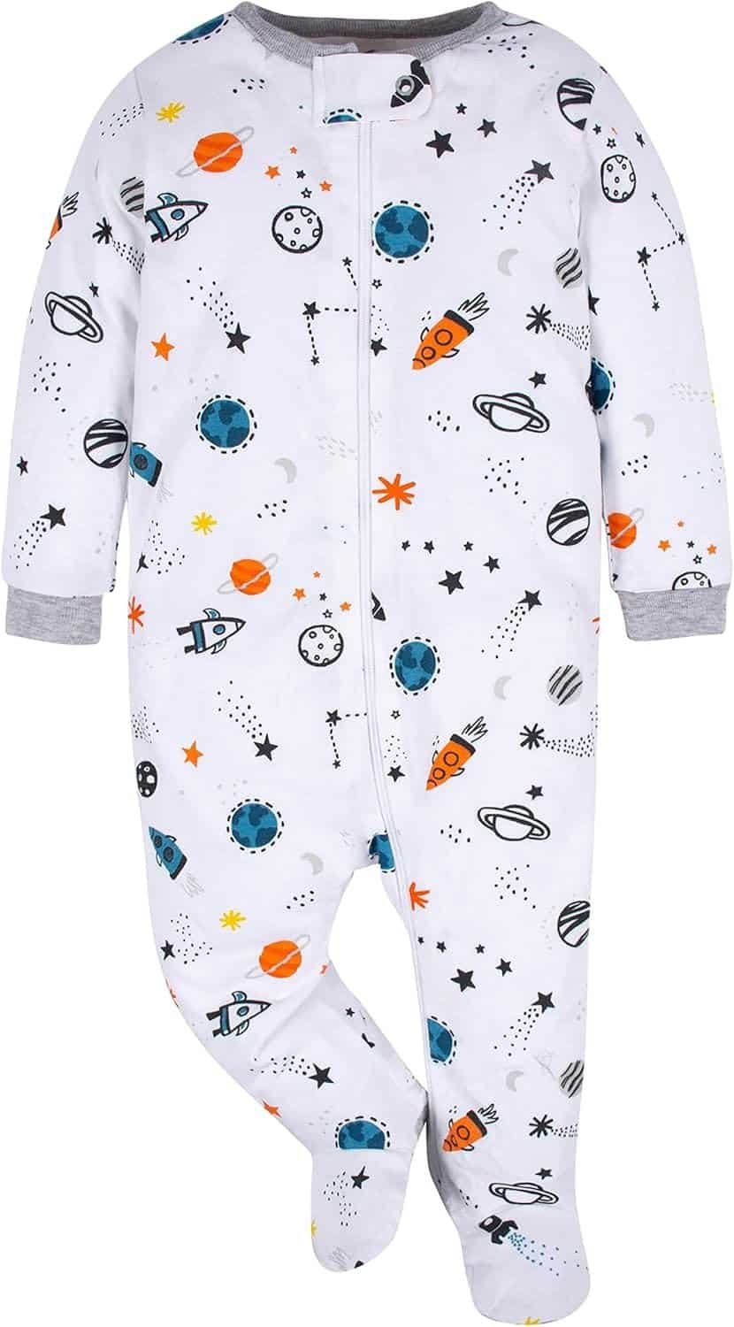 A white baby onesie with a zipper, featuring a space-themed print of rockets, planets, stars, and moons in blue, orange, and black.