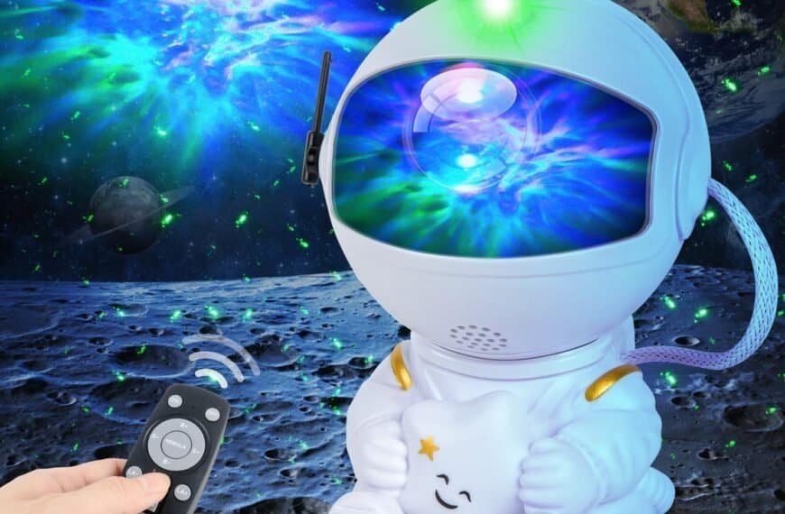 A person holds a remote control, facing a small astronaut-shaped projector that displays colorful lights and stars onto a space-themed background.