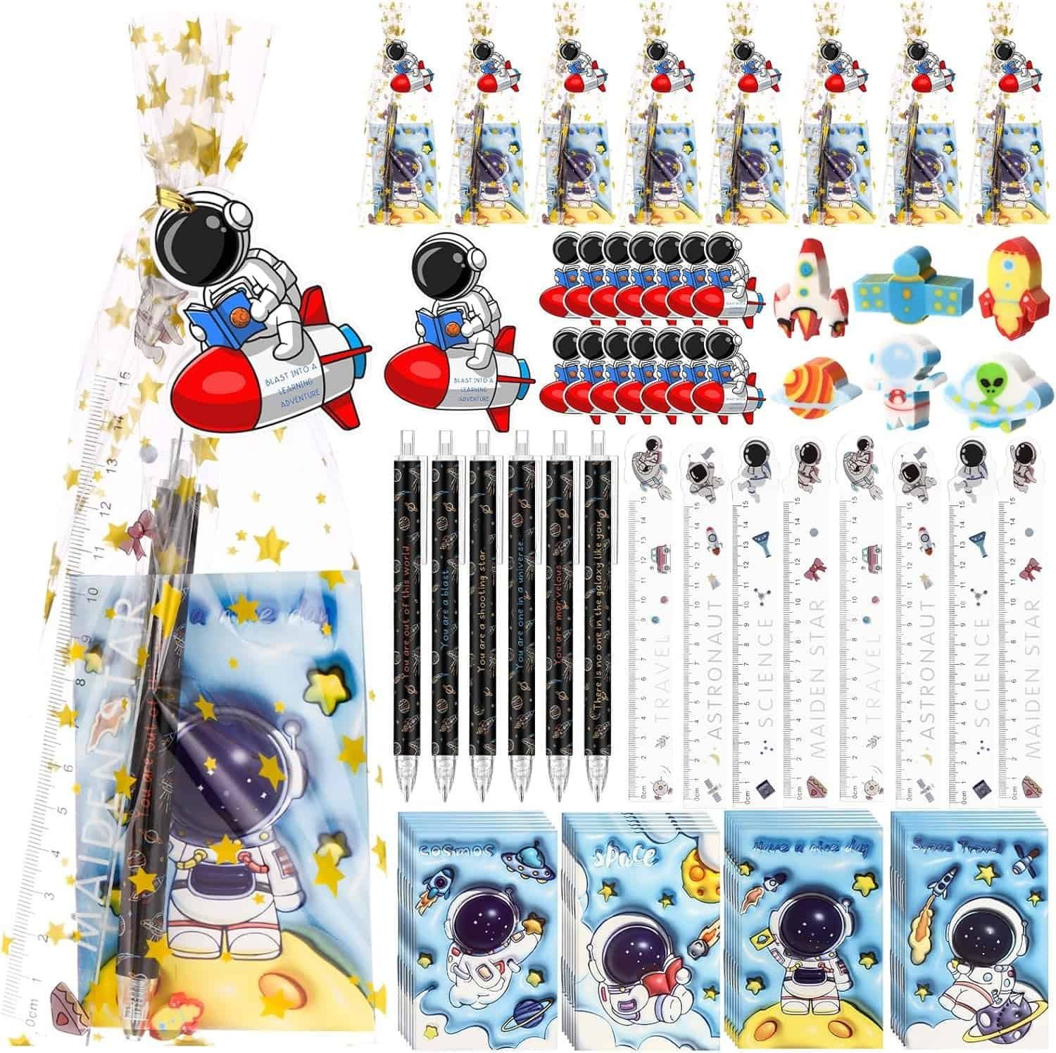 A stationery set with astronaut-themed pens, pencils, rulers, erasers, notebooks, keychains, and stickers, all arranged neatly with a gift bag in the background.