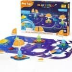A solar system board game set with colorful planets, alien figures, informational flags, and a box labeled "Mapology Solar System" for ages 4 and up.
