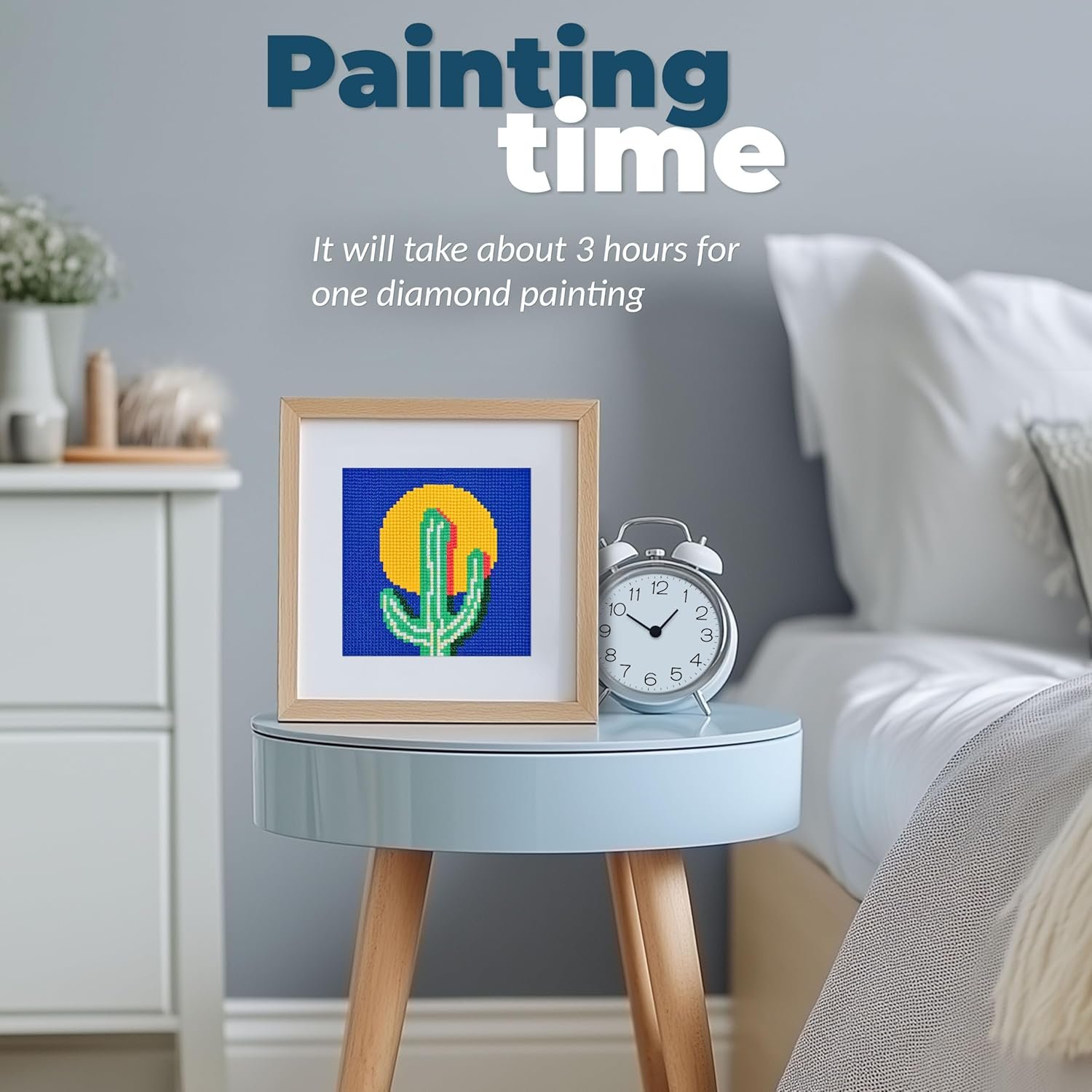 Framed diamond painting of a cactus with a yellow sun on a blue background sits on a round nightstand next to a silver clock in a modern bedroom. Text reads: "Painting time" and timing details.