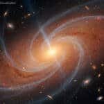 A bright, glowing spiral galaxy with swirling arms and several red galaxies in the background; labeled “GALACTIC RAIN: Slow Inflow Visualization.”.