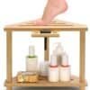 A wooden foot rest with a person’s foot on top, featuring a shelf below holding lotion bottles, a soap bar, and skincare containers.