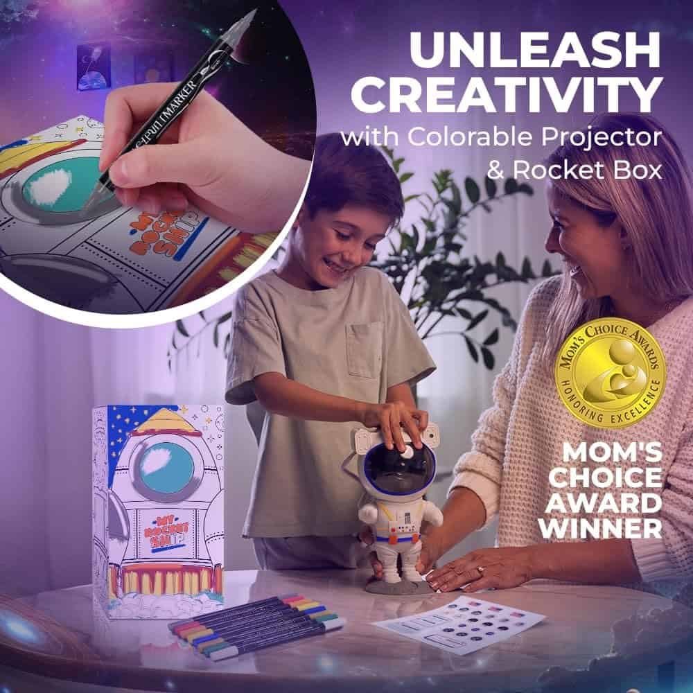 A child and an adult decorate a rocket-themed projector toy and box with markers. The product displays a Mom's Choice Award badge and the text "Unleash Creativity.
