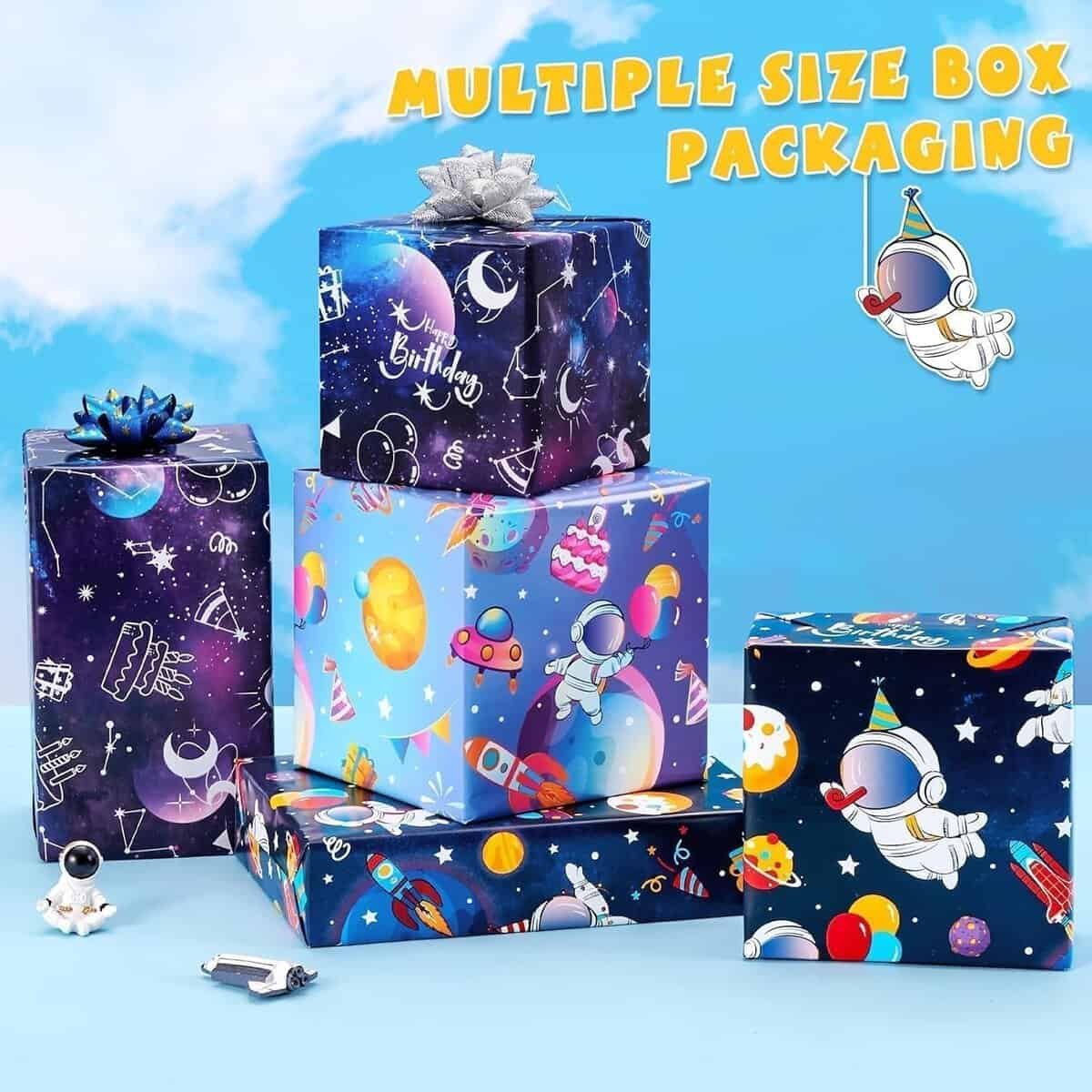 Five space-themed gift boxes of various sizes are stacked together, surrounded by astronaut and spaceship decorations. The text "Multiple Size Box Packaging" appears at the top right.