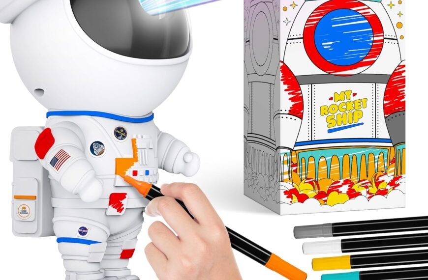 A person colors a white astronaut figurine with markers. Next to it is a partially colored rocket ship drawing and several colored markers.