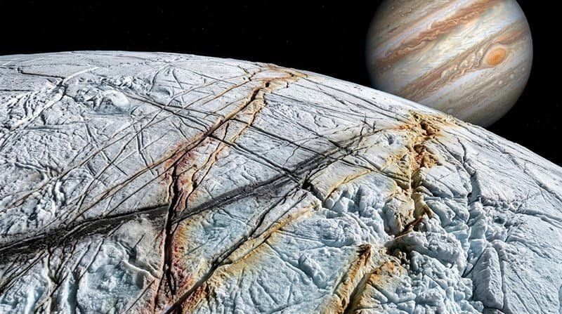 A close-up view of Europa’s cracked, icy surface—hinting at traces of ammonia on Europa—with Jupiter and its cloud bands visible in the background in space.