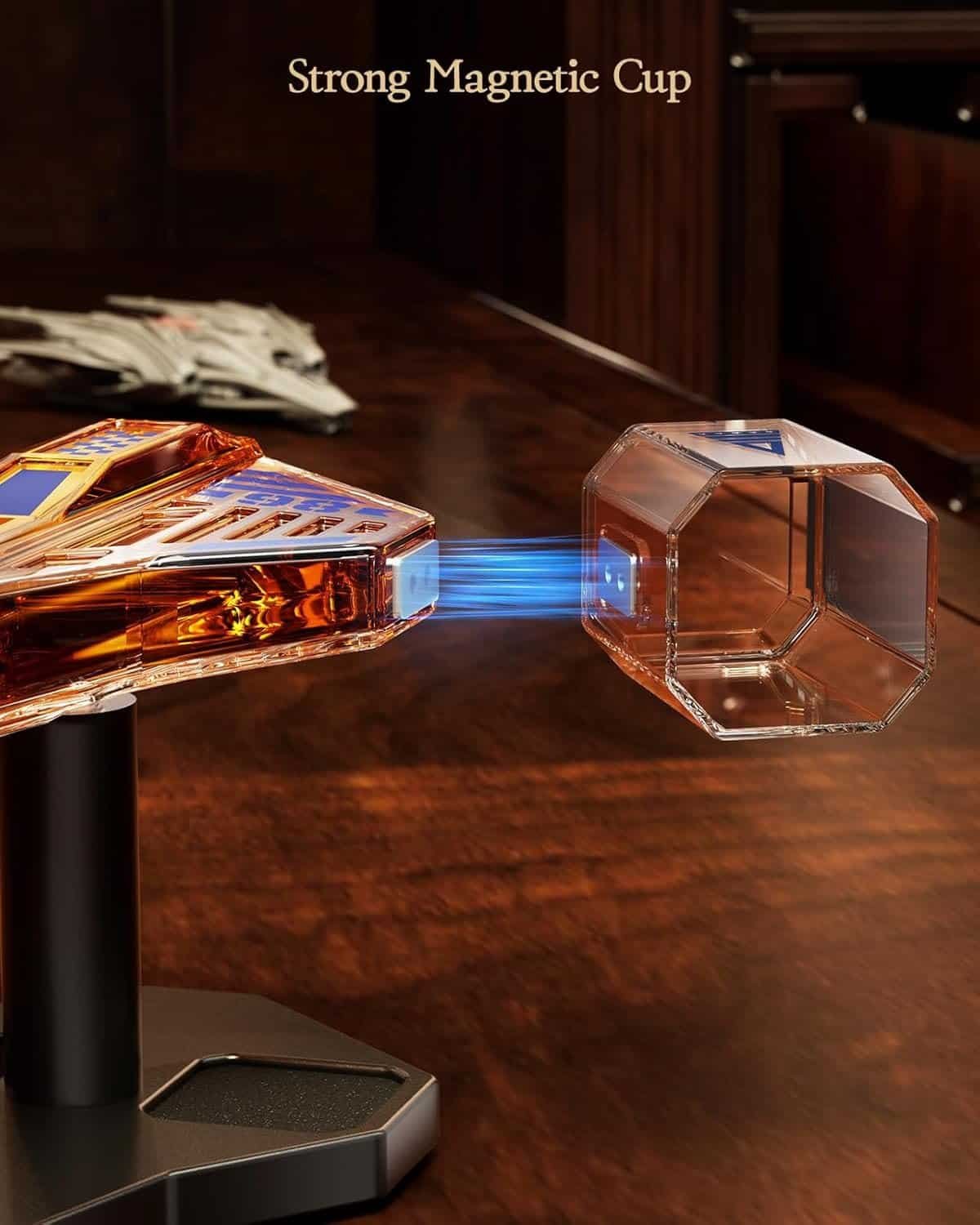 A transparent, hexagonal cup hovers near a base on a wooden surface, connected by a visible magnetic force, with the text "Strong Magnetic Cup" above.