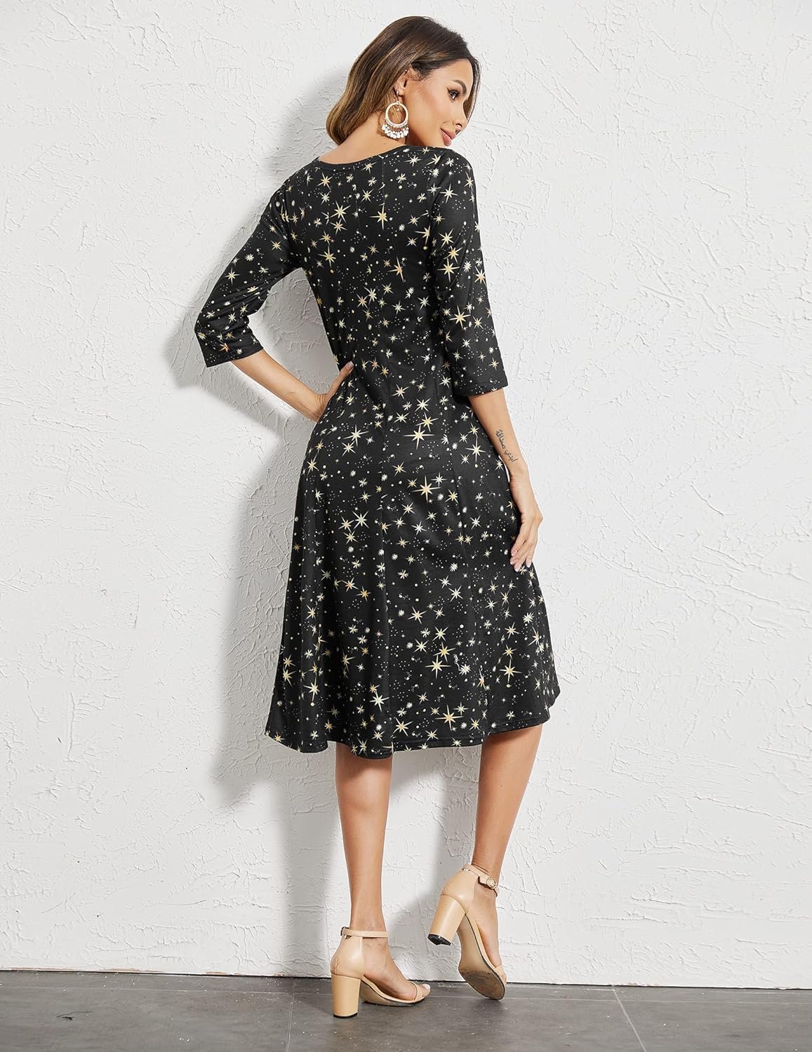 Woman posing in a starry gown with three-quarter sleeves, paired with beige heels.