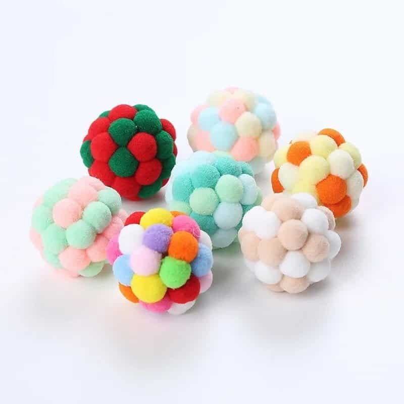 A group of colorful pom pom balls auto-drafted onto a white surface.