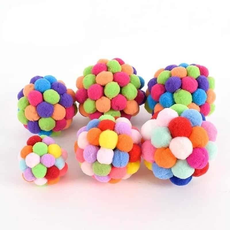 A group of colorful pom pom balls, perfect for craft industry projects, on a white surface.