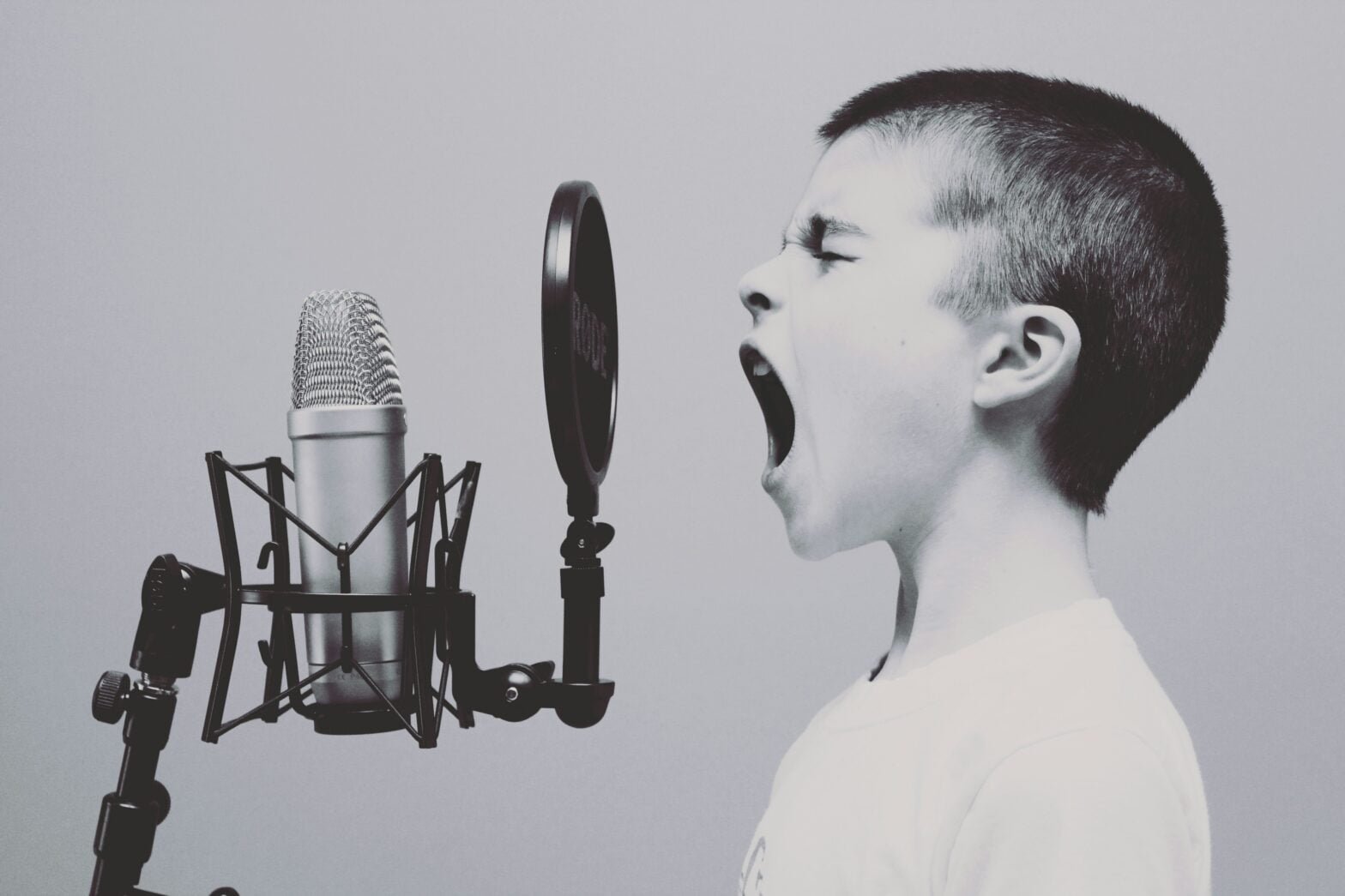 Young boy singing passionately into a studio microphone.