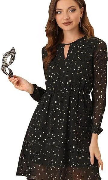 A woman in a black metallic star-patterned dress holding a masquerade mask.