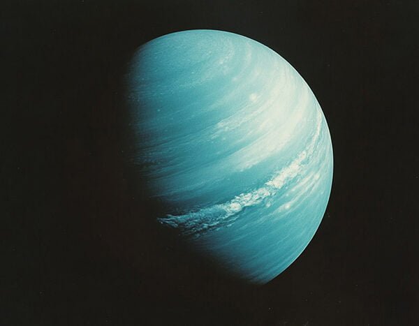 The 9 Planets in Our Solar System 2 A blue-green planet with visible cloud bands, partially illuminated against a dark background — Uranus in all its serene beauty.