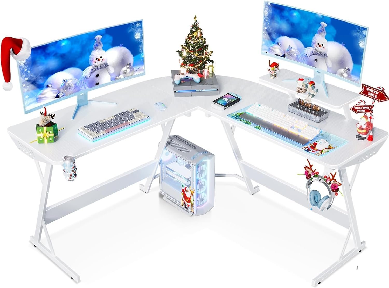 A white L-shaped computer desk decorated with Christmas-themed items, dual monitors displaying snowman wallpaper, a Christmas tree, Santa hat, and ornaments. The CPU is placed on the floor under the desk.