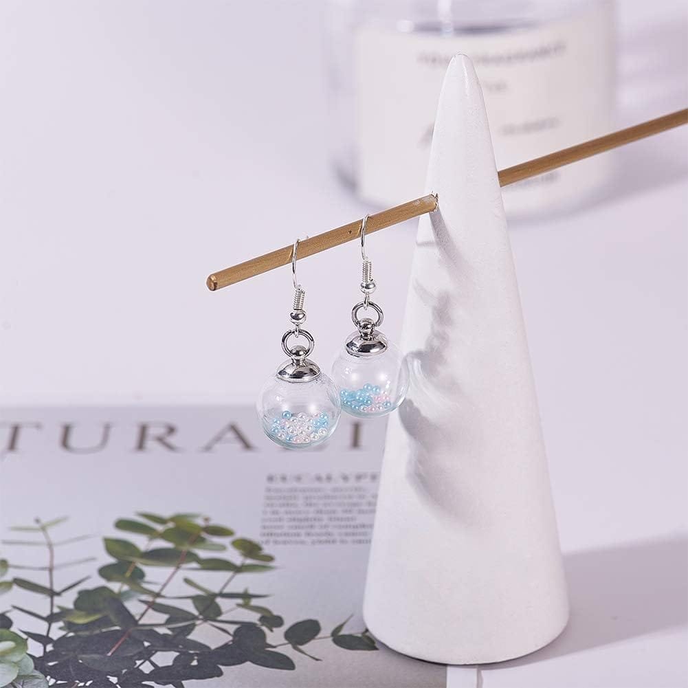 A pair of silver drop earrings with transparent globes, hanging on a triangular white stand.