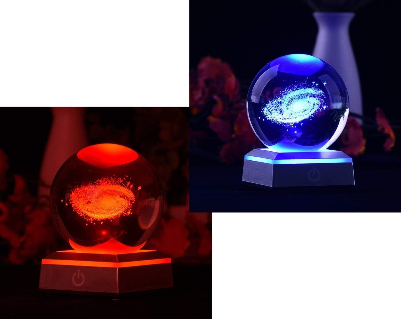A glass sphere displaying a galaxy design with red and blue illumination, placed on a lit base.
