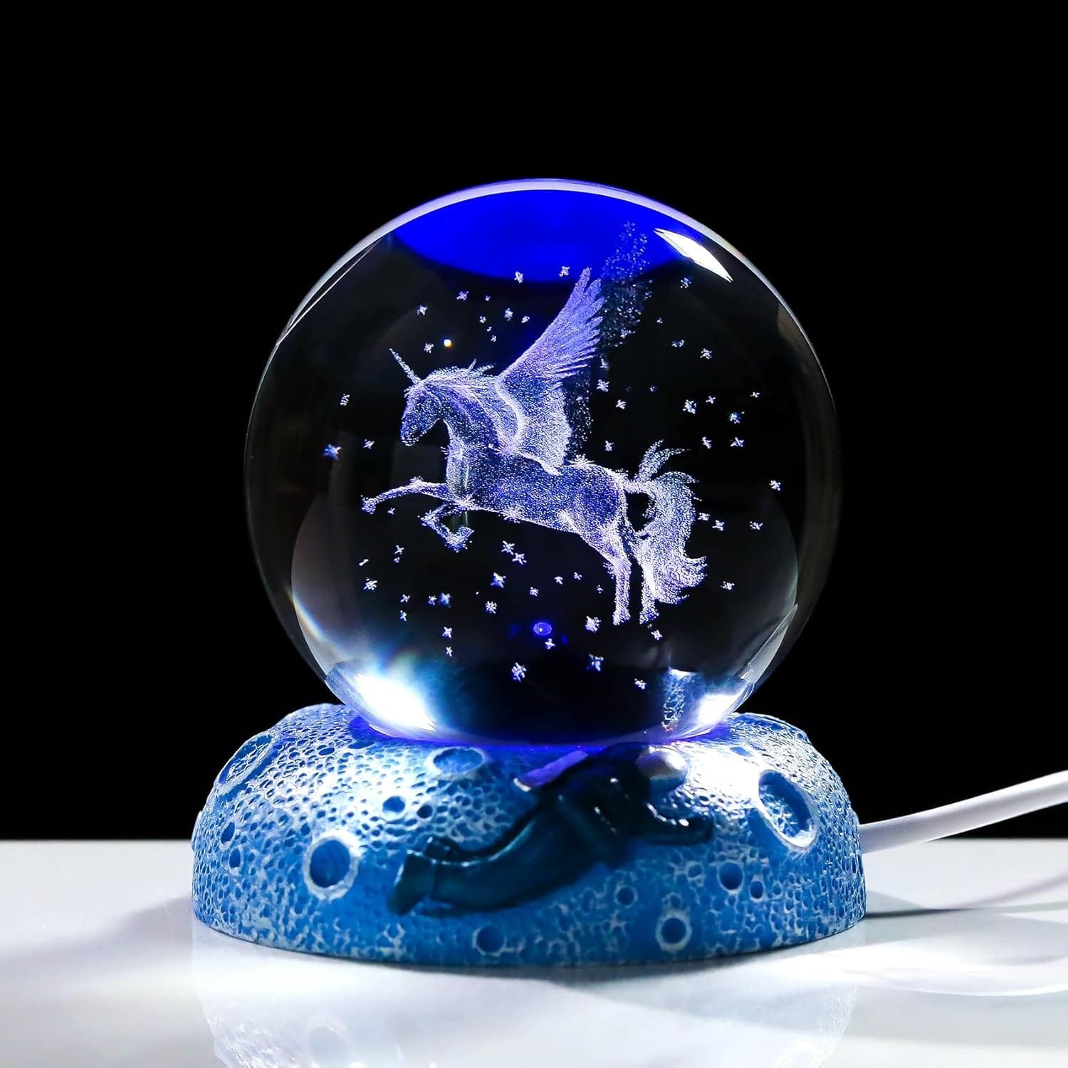 A glass globe with a 3D unicorn design and stars inside, set on a blue, textured base with a lightning motif.