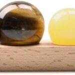 A wooden base holds a row of nine spherical stones of varying sizes and colors, including clear, red, brown, yellow, green, blue, and purple.