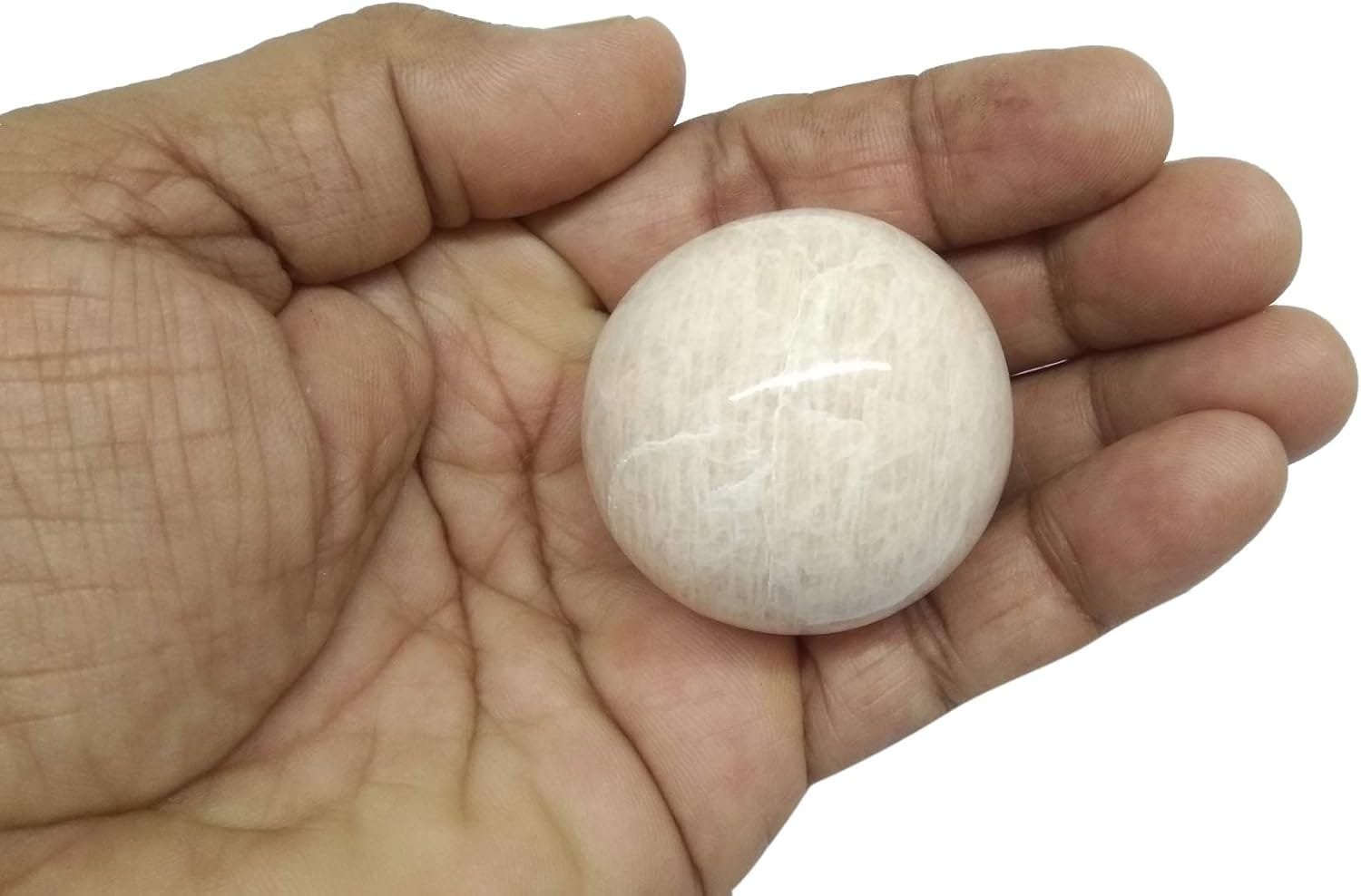 A hand holding a smooth, round, white stone.