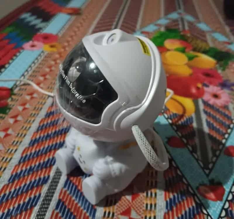 On a vibrant, patterned backdrop, the Your World with the Astronaut Galaxy Projector sits confidently, featuring a toy astronaut figure equipped with a reflective helmet and white suit, ready to explore the galaxy.