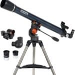 A Celestron AstroMaster 70 telescope on a tripod with two eyepieces and a red dot finder scope.