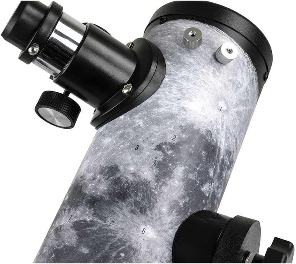 Close-up of a telescope tube with a lunar surface design, numbered markings, and adjustment knobs visible.