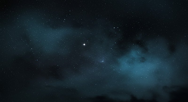 A night sky filled with numerous stars, some shining brighter than others, with wispy clouds partially obscuring parts of the sky.