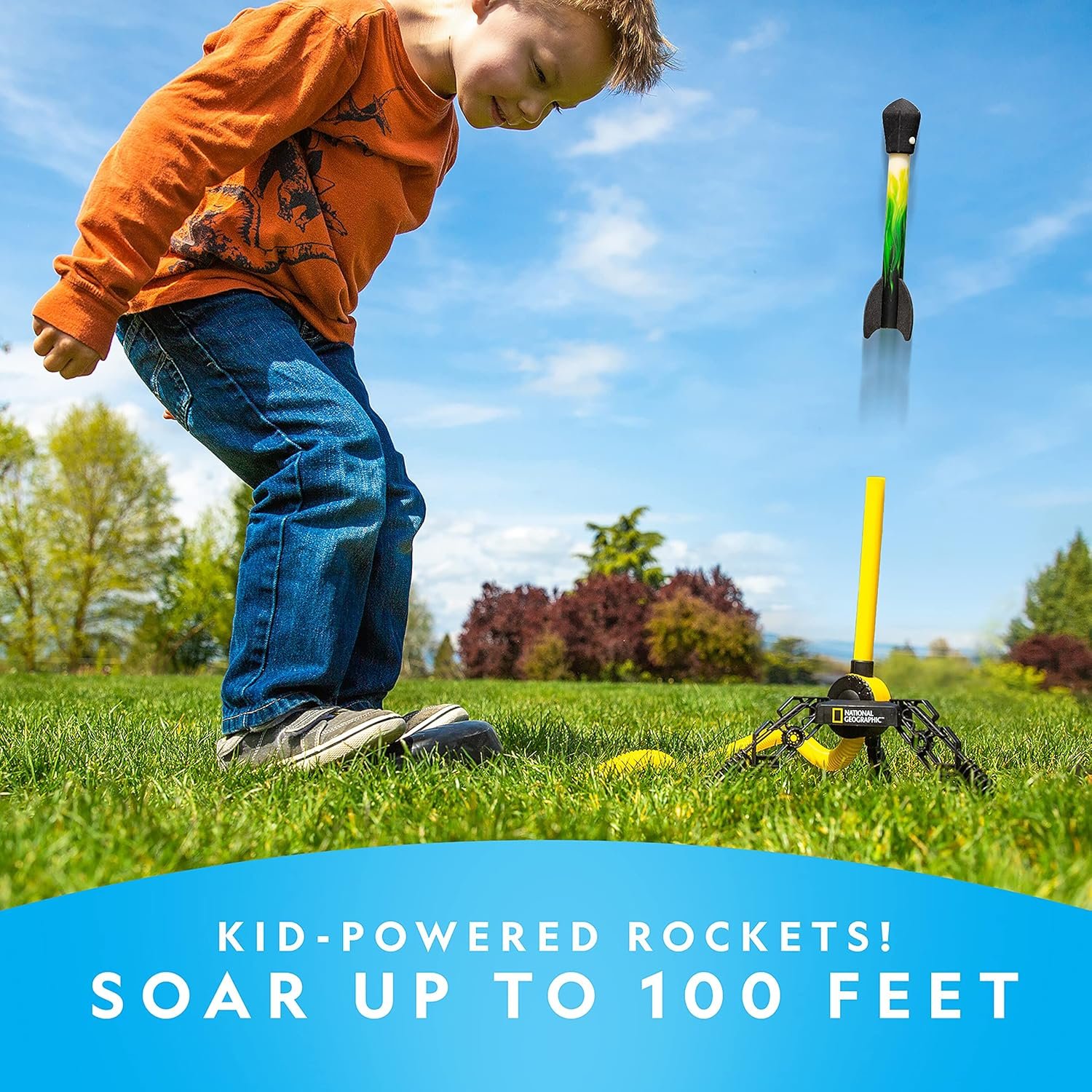 A young boy stomps on a launch pad, sending a toy rocket into the air on a grassy field under a blue sky. Text reads: "Kid-powered rockets! Soar up to 100 feet.