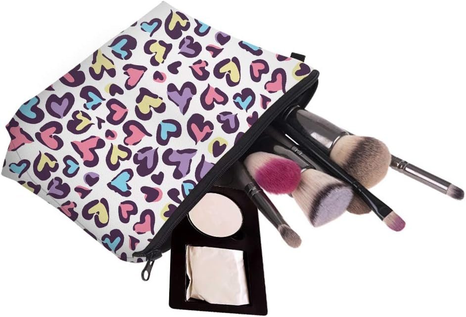 A zippered makeup bag with a colorful heart pattern, several makeup brushes, a compact mirror, and a powder compact partially visible.
