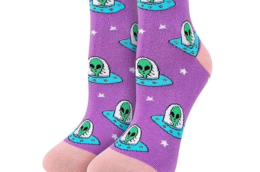 Purple socks with pink accents featuring a repeated pattern of green aliens in UFOs; includes SockFun packaging and a close-up of the sock design.