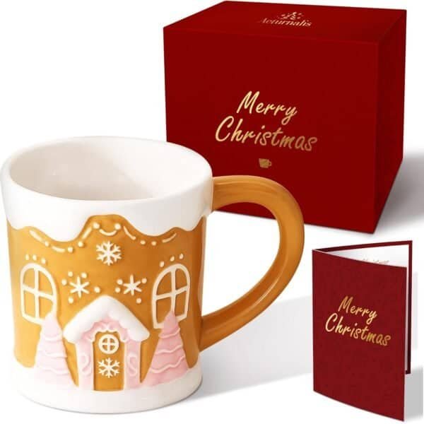A ceramic mug with a gingerbread house design is shown next to a red gift box and a matching "Merry Christmas" greeting card.