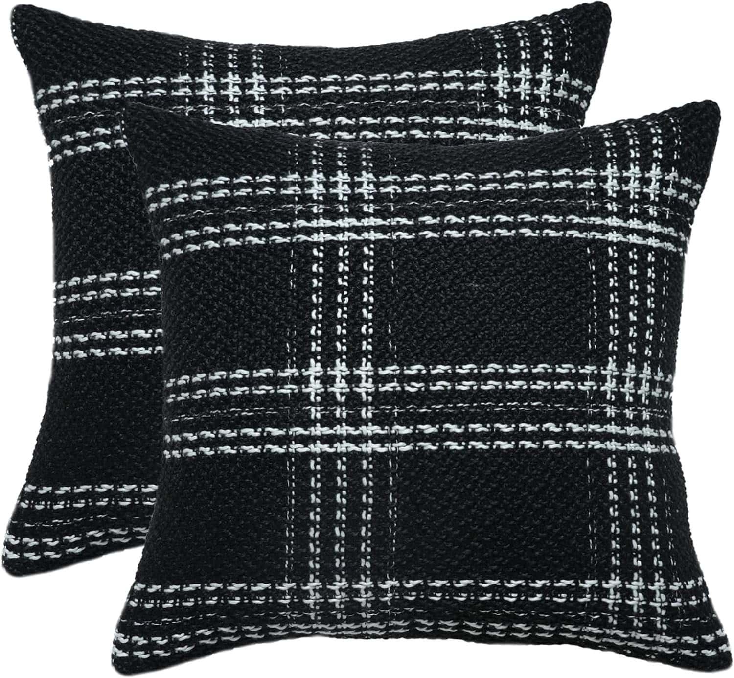 Two square black throw pillows with a white and gray plaid pattern, placed side by side with one slightly overlapping the other.