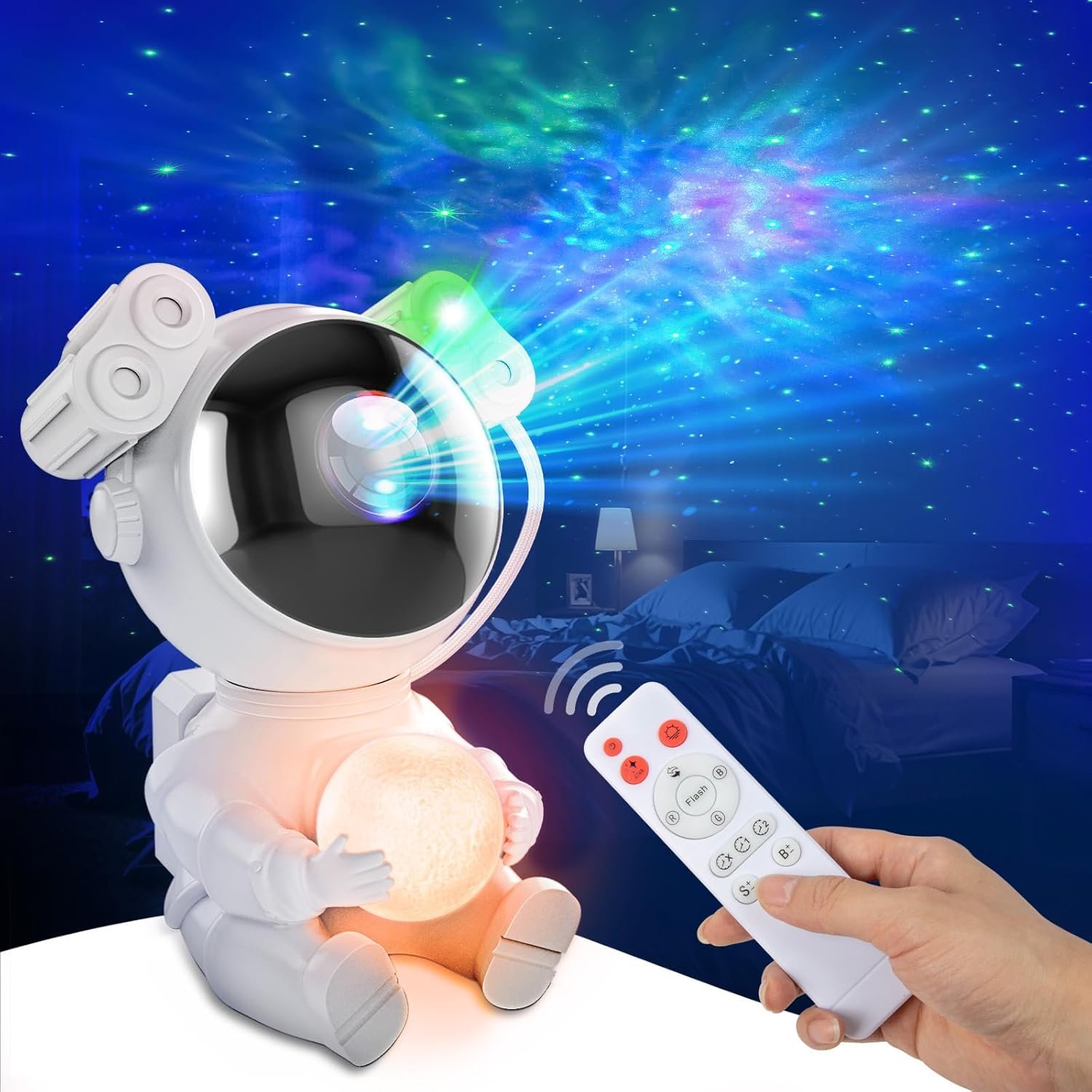 A hand holds a remote control aimed at an astronaut-shaped projector that displays colorful star patterns on the ceiling of a dark bedroom.