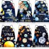 Six drawstring bags with space-themed designs featuring planets, astronauts, stars, and motivational phrases like "EXPLORE THE UNIVERSE" and "REACH FOR THE STARS.